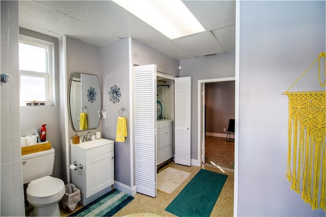 bathroom with a paneled ceiling, toilet, and vanity