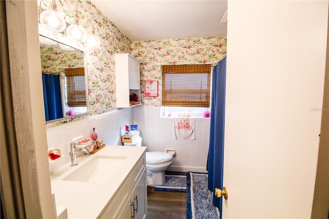 bathroom with walk in shower, wood-type flooring, vanity, toilet, and tile walls