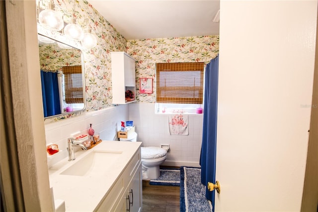 130 63rd St S, Saint Petersburg, FL 33707 - bathroom featuring wallpapered walls, a wainscoted wall, wood finished floors, vanity, and toilet