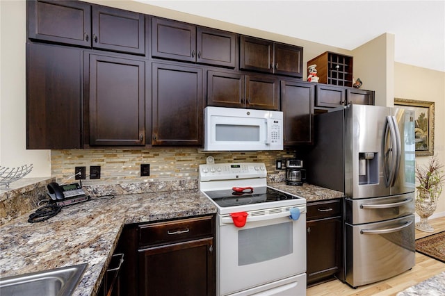 kitchen with stone counters, dark brown cabinets, backsplash, and white appliances