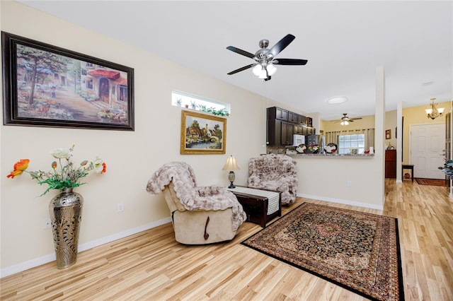 sitting room featuring ceiling fan with notable chandelier and light hardwood / wood-style floors