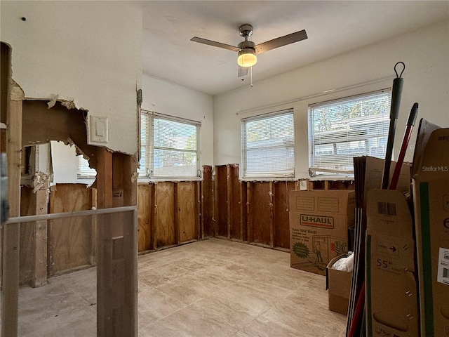 interior space with ceiling fan and wooden walls