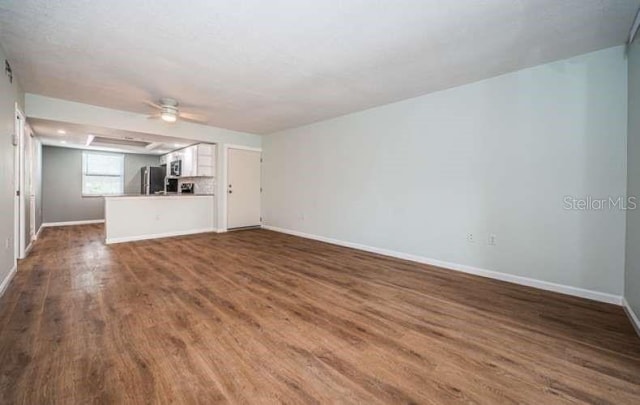 unfurnished living room featuring dark hardwood / wood-style floors and ceiling fan