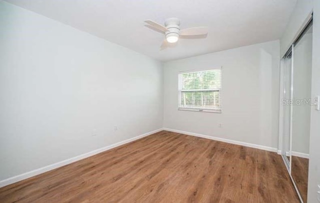 unfurnished bedroom featuring ceiling fan, a closet, and wood-type flooring