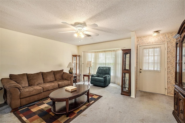 living room featuring ceiling fan, light colored carpet, and a textured ceiling