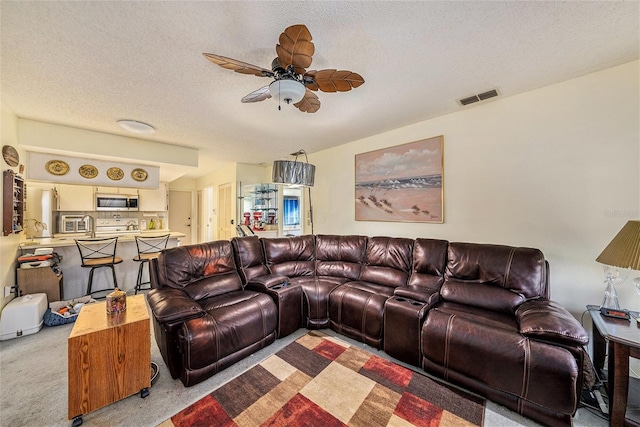 living room featuring light carpet, a textured ceiling, and ceiling fan