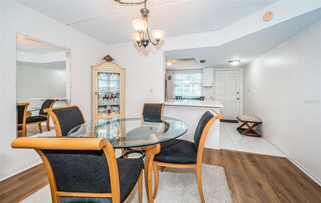 dining room with ceiling fan with notable chandelier and light wood-type flooring