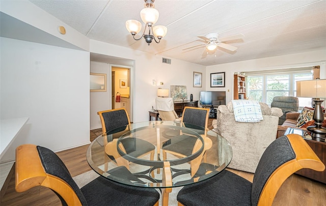 dining space featuring ceiling fan with notable chandelier, a textured ceiling, and hardwood / wood-style flooring