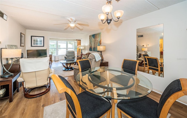 dining area featuring ceiling fan with notable chandelier, wood-type flooring, and a textured ceiling