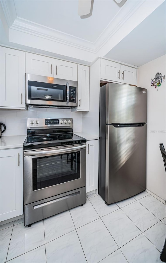 kitchen with white cabinets, stainless steel appliances, tasteful backsplash, and ornamental molding