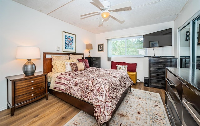 bedroom featuring hardwood / wood-style floors, a textured ceiling, a closet, and ceiling fan