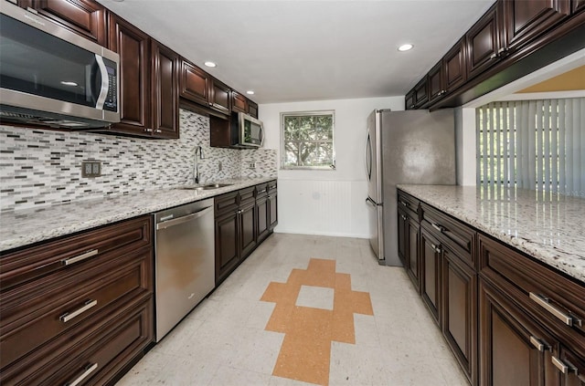 kitchen featuring sink, decorative backsplash, dark brown cabinets, light stone counters, and stainless steel appliances