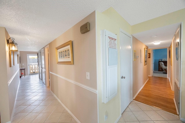 hallway featuring light wood-type flooring and a textured ceiling