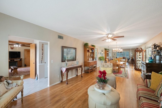 living room with light hardwood / wood-style floors, a notable chandelier, and a textured ceiling