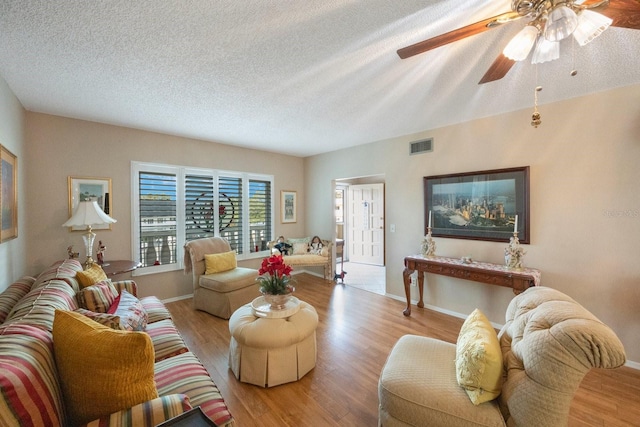 living room featuring ceiling fan, a textured ceiling, and light hardwood / wood-style floors