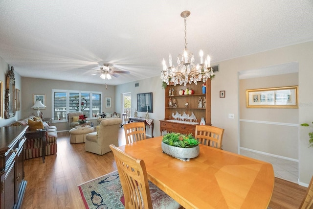 dining room with a textured ceiling, light hardwood / wood-style floors, and ceiling fan with notable chandelier