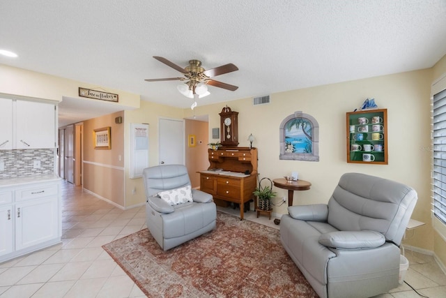 sitting room with a textured ceiling, ceiling fan, and light tile patterned floors