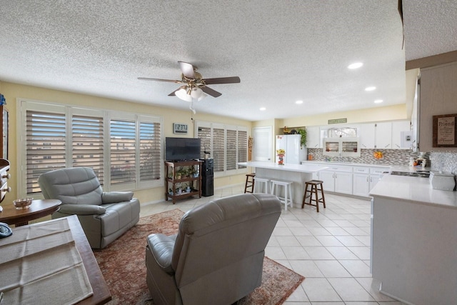 tiled living room with ceiling fan and a textured ceiling