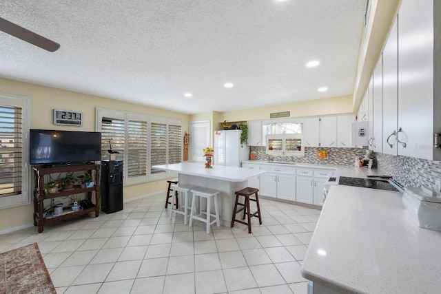 kitchen with a kitchen island, white cabinetry, a healthy amount of sunlight, and a kitchen breakfast bar