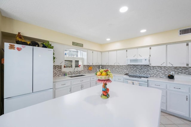 kitchen featuring white cabinets, decorative backsplash, sink, light tile patterned floors, and white appliances