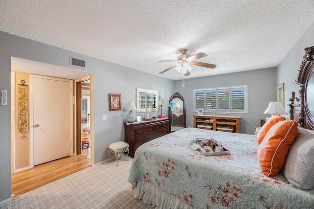 bedroom with hardwood / wood-style flooring, ceiling fan, and a textured ceiling