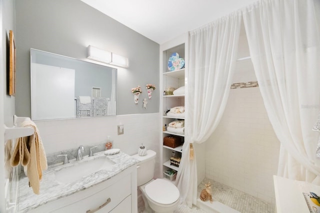 bathroom featuring walk in shower, vanity, toilet, and tile walls