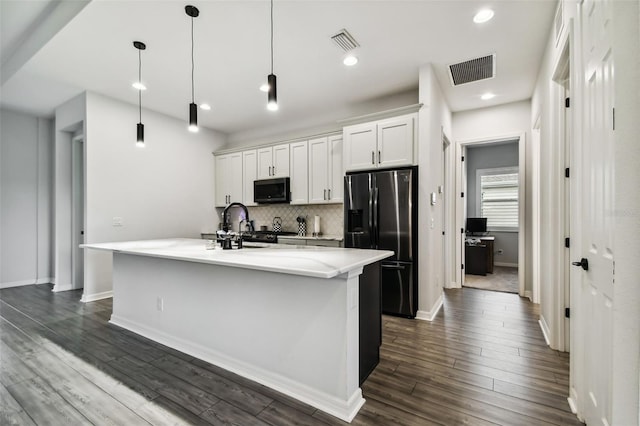 kitchen featuring white cabinetry, stainless steel appliances, dark hardwood / wood-style flooring, decorative light fixtures, and a center island with sink