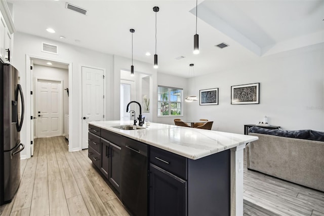 kitchen with sink, dishwasher, light hardwood / wood-style flooring, stainless steel fridge, and a kitchen island with sink