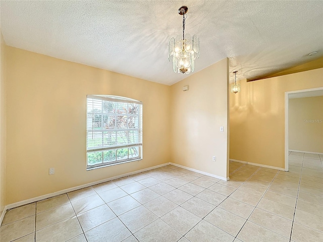 spare room with a textured ceiling, light tile patterned floors, and an inviting chandelier