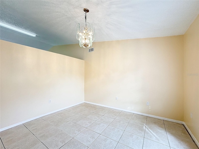 tiled empty room featuring vaulted ceiling, a notable chandelier, and a textured ceiling