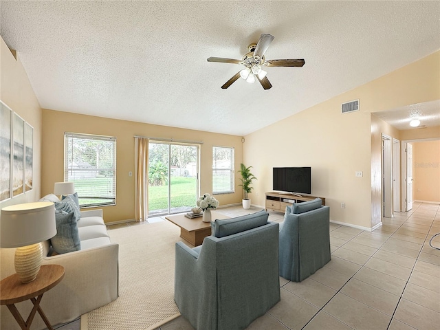 living room with a textured ceiling, ceiling fan, vaulted ceiling, and light tile patterned floors