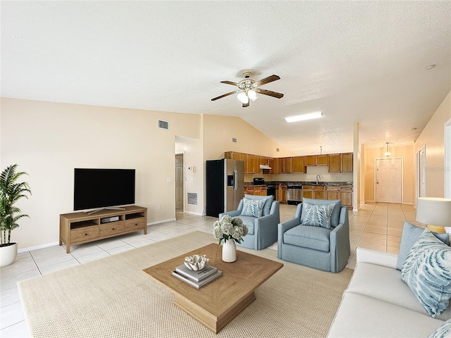 tiled living room with ceiling fan, a textured ceiling, sink, and lofted ceiling