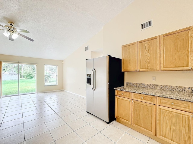 kitchen featuring light stone counters, stainless steel fridge with ice dispenser, light tile patterned floors, a textured ceiling, and light brown cabinetry