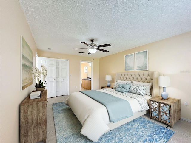 tiled bedroom featuring ceiling fan, a textured ceiling, and a closet