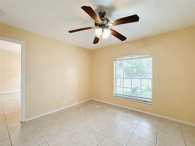 empty room with a textured ceiling, ceiling fan, and light tile patterned floors