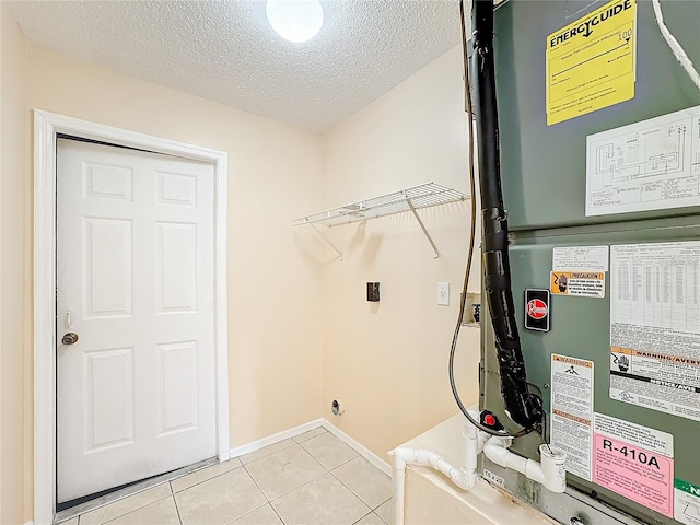 clothes washing area featuring a textured ceiling, light tile patterned floors, and heating unit