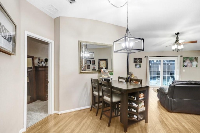 dining room featuring light wood-type flooring and ceiling fan with notable chandelier