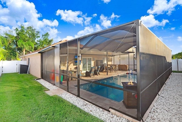 rear view of house featuring a lawn, a fenced in pool, glass enclosure, and a patio area