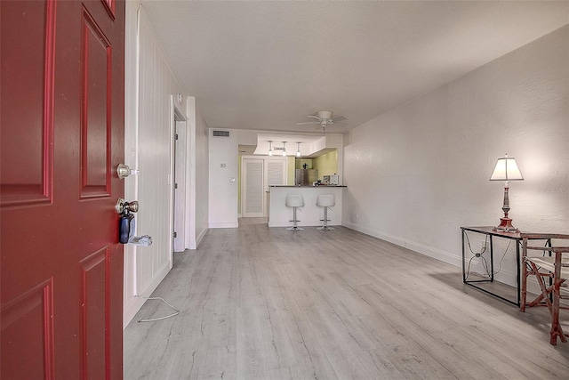 foyer with a textured ceiling, light wood-type flooring, and ceiling fan