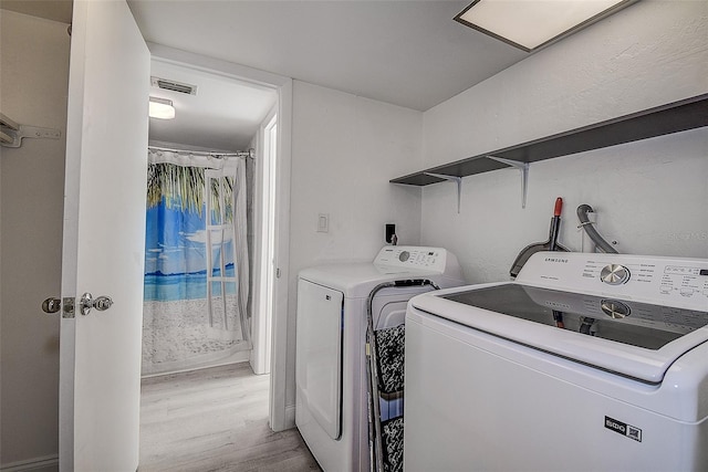 clothes washing area with light wood-type flooring and washer and dryer