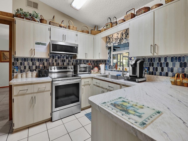 kitchen with stainless steel appliances, lofted ceiling, a textured ceiling, sink, and light tile patterned flooring