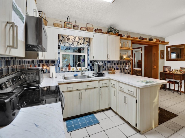 kitchen featuring sink, kitchen peninsula, tasteful backsplash, light tile patterned floors, and black range