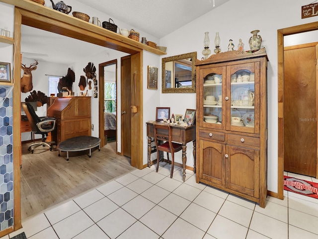 home office featuring light wood-type flooring, a textured ceiling, and vaulted ceiling