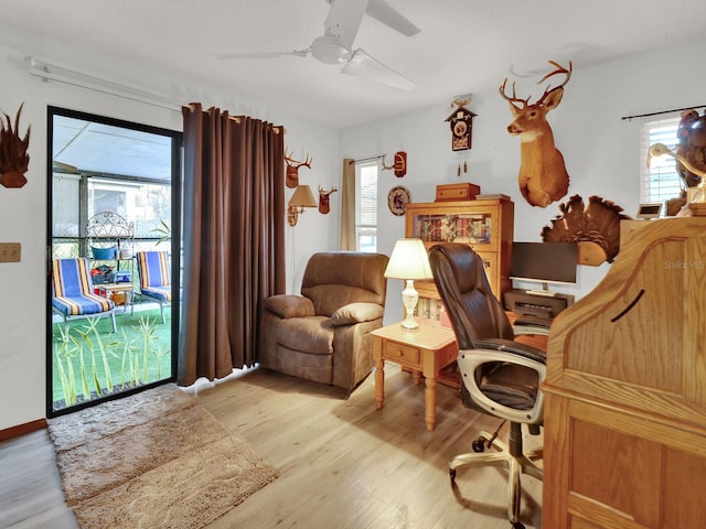 office space with light wood-type flooring, a healthy amount of sunlight, and ceiling fan