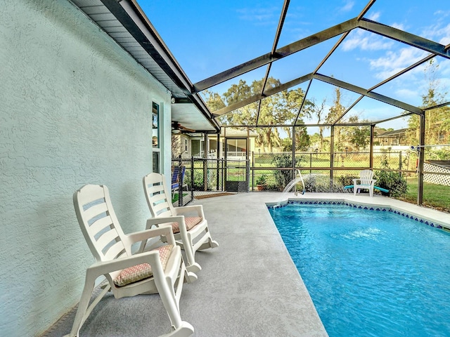 view of swimming pool with glass enclosure, a patio, and ceiling fan