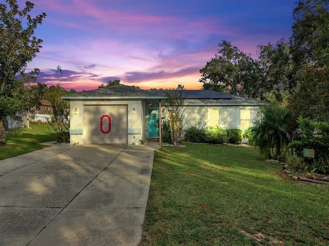 ranch-style home with solar panels and a lawn