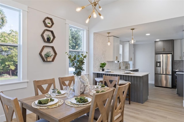 dining space with sink, an inviting chandelier, and light hardwood / wood-style floors