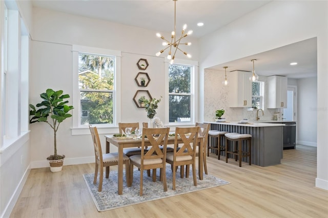 dining space featuring sink, light hardwood / wood-style flooring, and a notable chandelier