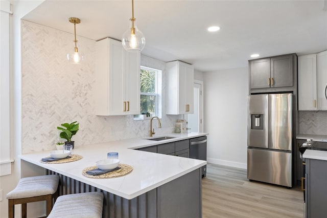 kitchen with sink, decorative light fixtures, kitchen peninsula, and appliances with stainless steel finishes