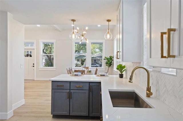 kitchen with sink, gray cabinetry, backsplash, hanging light fixtures, and light hardwood / wood-style floors